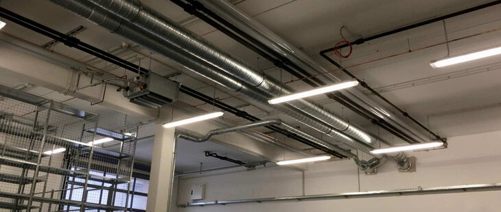 An Ketten abgehangene Leuchtstofflampen in einer Industriehalle